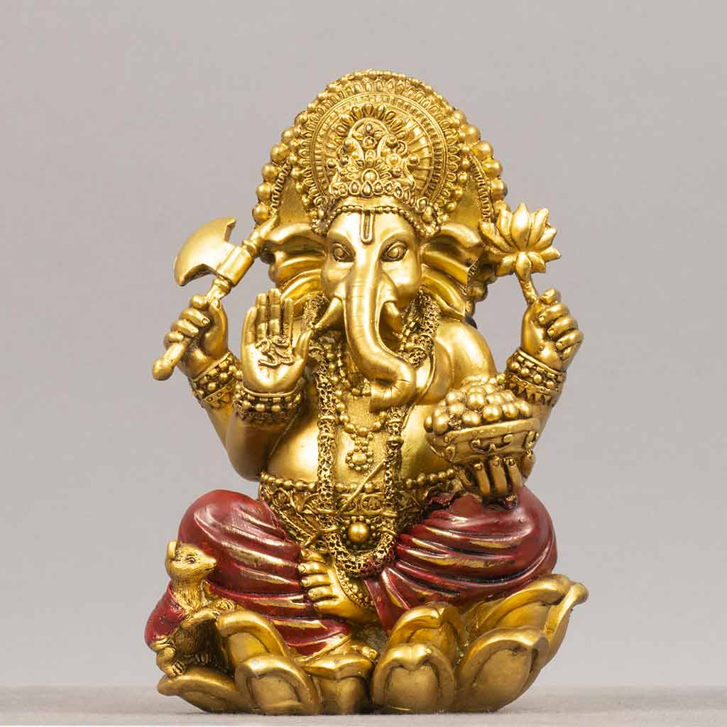 A golden statue of a god with an elephant head and multiple arms holding objects such as an axe, a bowl, and a lotus flower