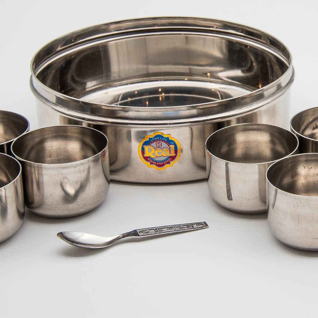 A set of stainless steel bowls with a spoon at the center on a light gray background