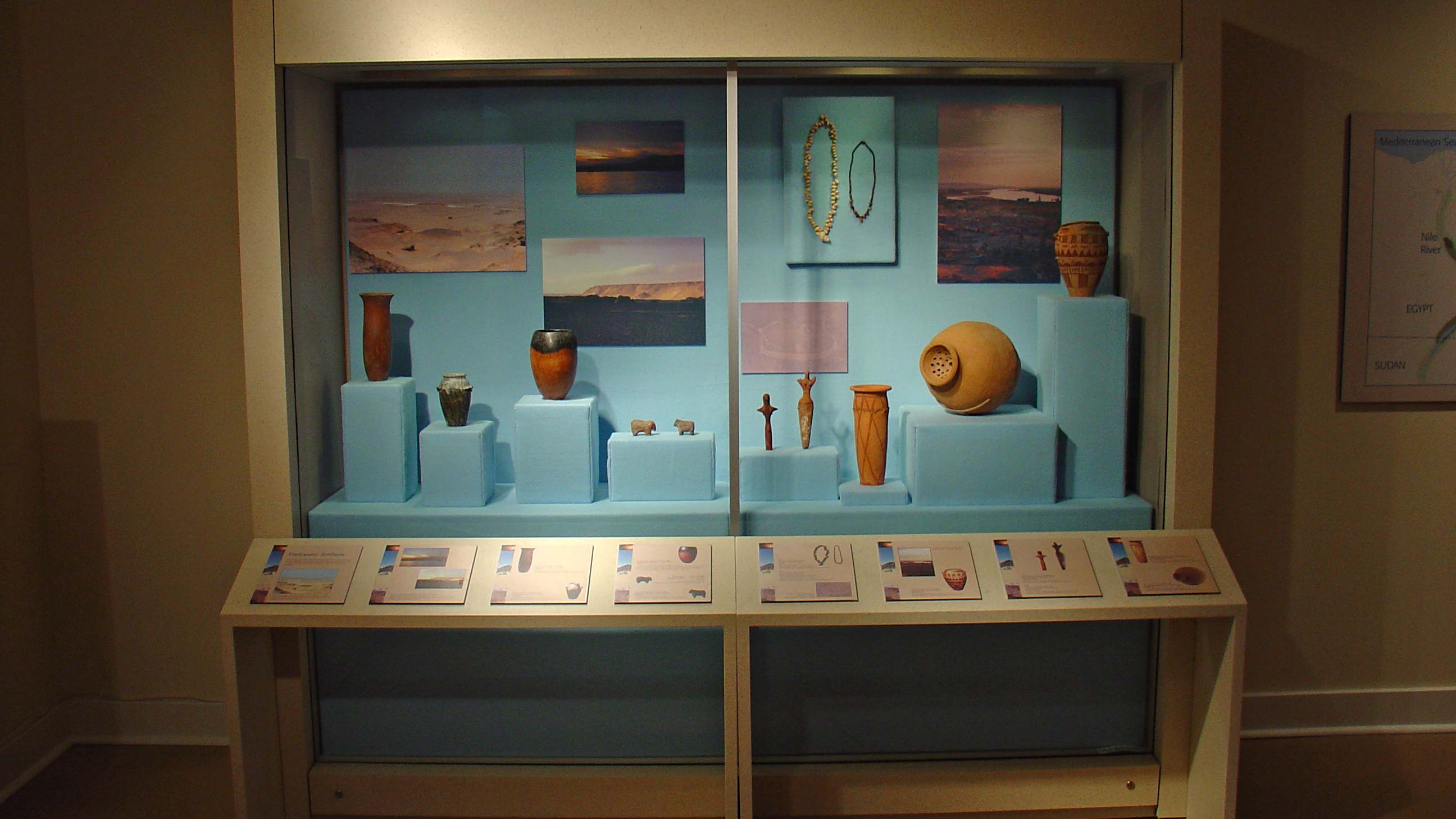 display case with pots and other artifacts and pictures