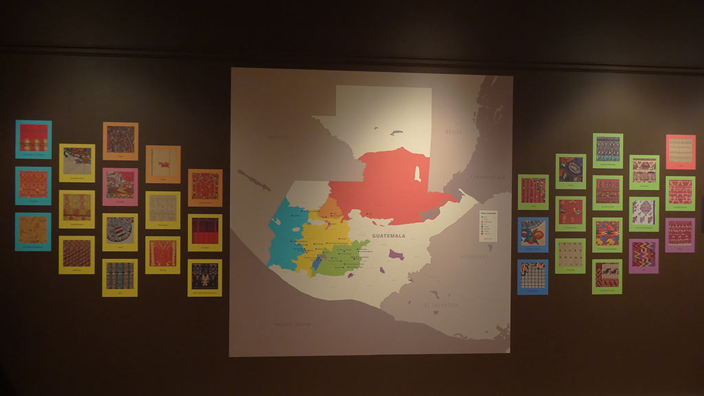 picture wall with small pieces of Maya art on it, with a larger piece showing where in Guatemala the Maya can be found
