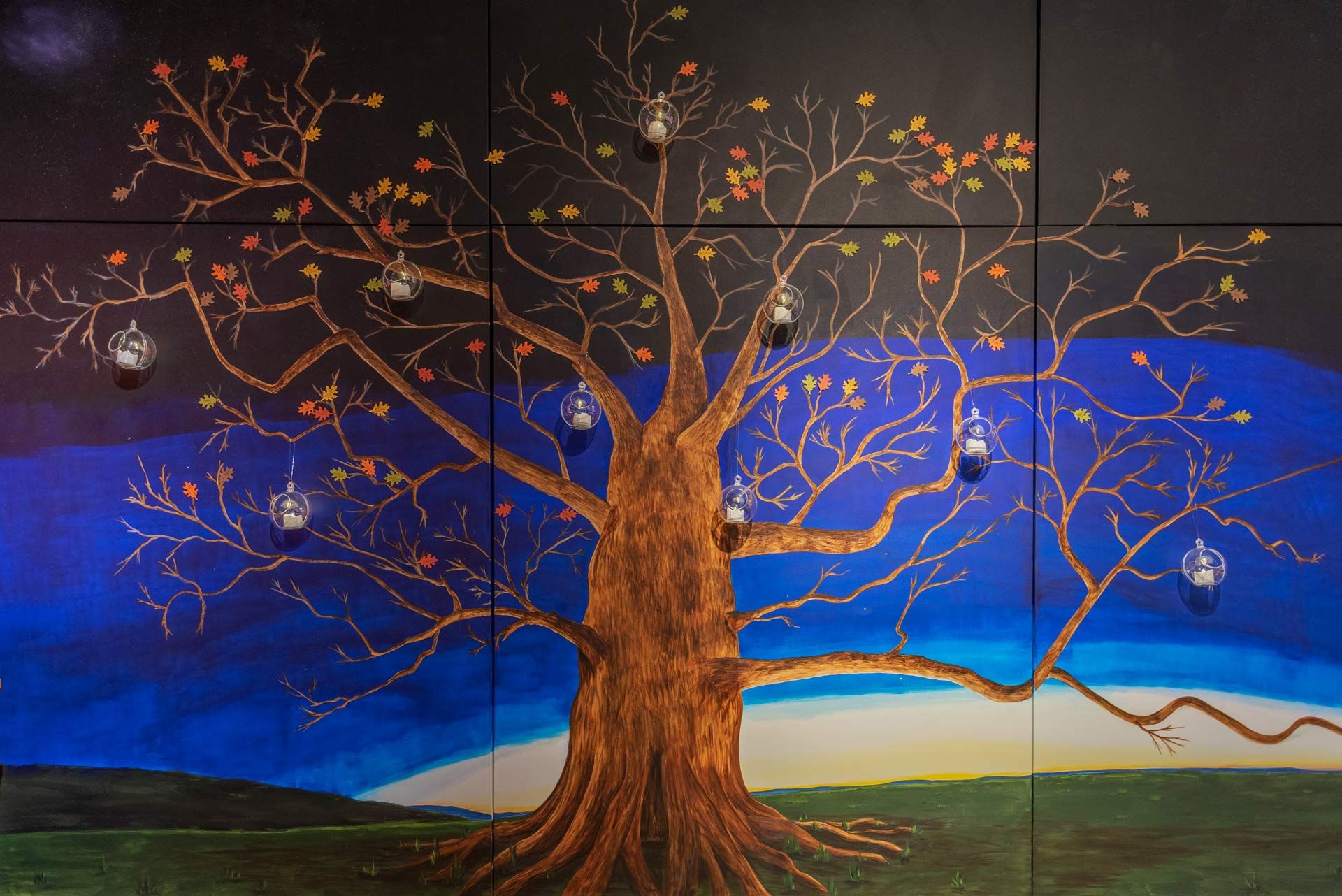 Painting of a large tree with a sunset in the background, and clear round containers attached to some branches