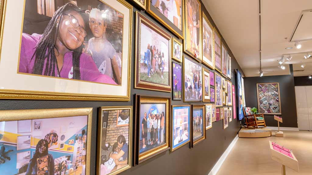 A collage of framed images of smiling black women on a wall