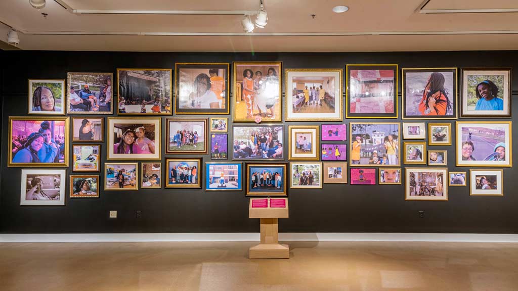 A collage of framed images of smiling black women on a wall