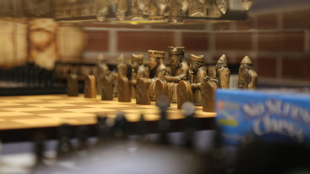 an angled right side shot of the brown chess pieces standing on a chessboard