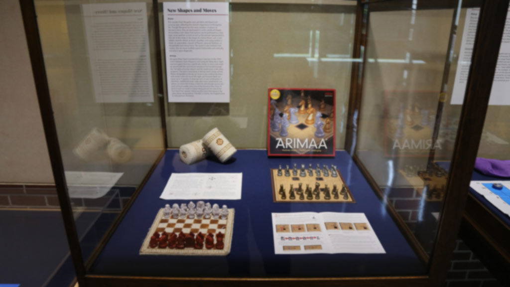 display case with a different type of chess game and its box and pieces, named 'arimaa'