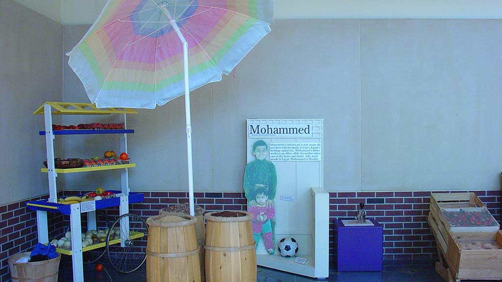 children in Mohammed section with a soccer ball, large umbrella, wooden bucket, vegetable and fruits