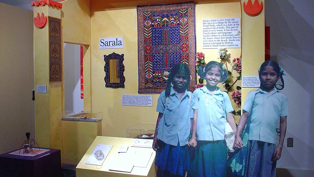 children in Sarala section, three girls wearing a white shirt and blue skirt and they are all holding hands