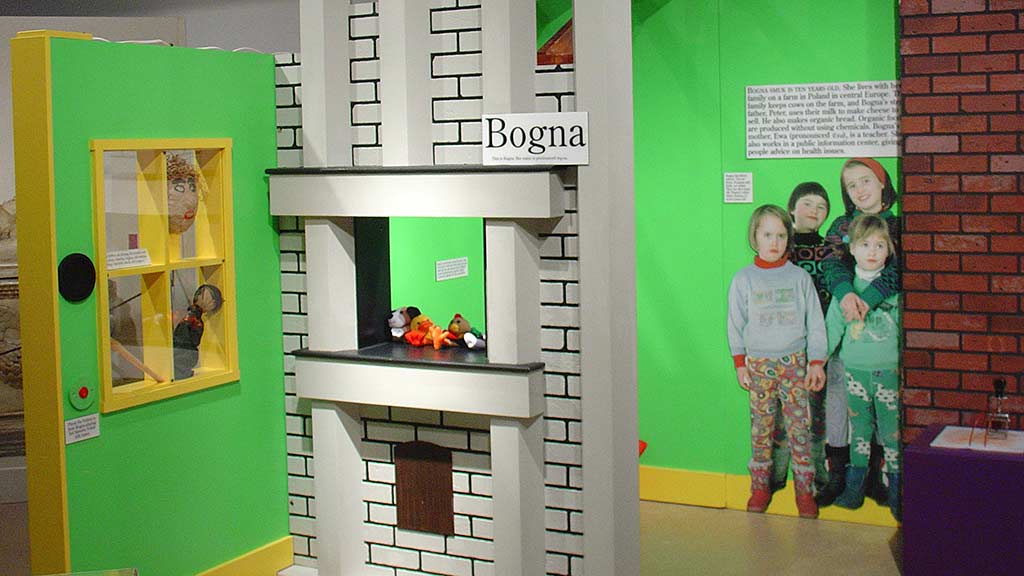 chidren in Bogna section, children wearing sweaters and cotton pants posed for a group picture, with a model fireplace not too far in front