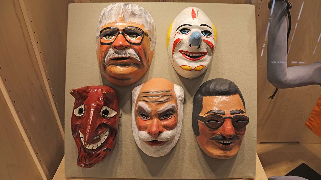 various masks depicting seemingly ordinary people and figures of fiction