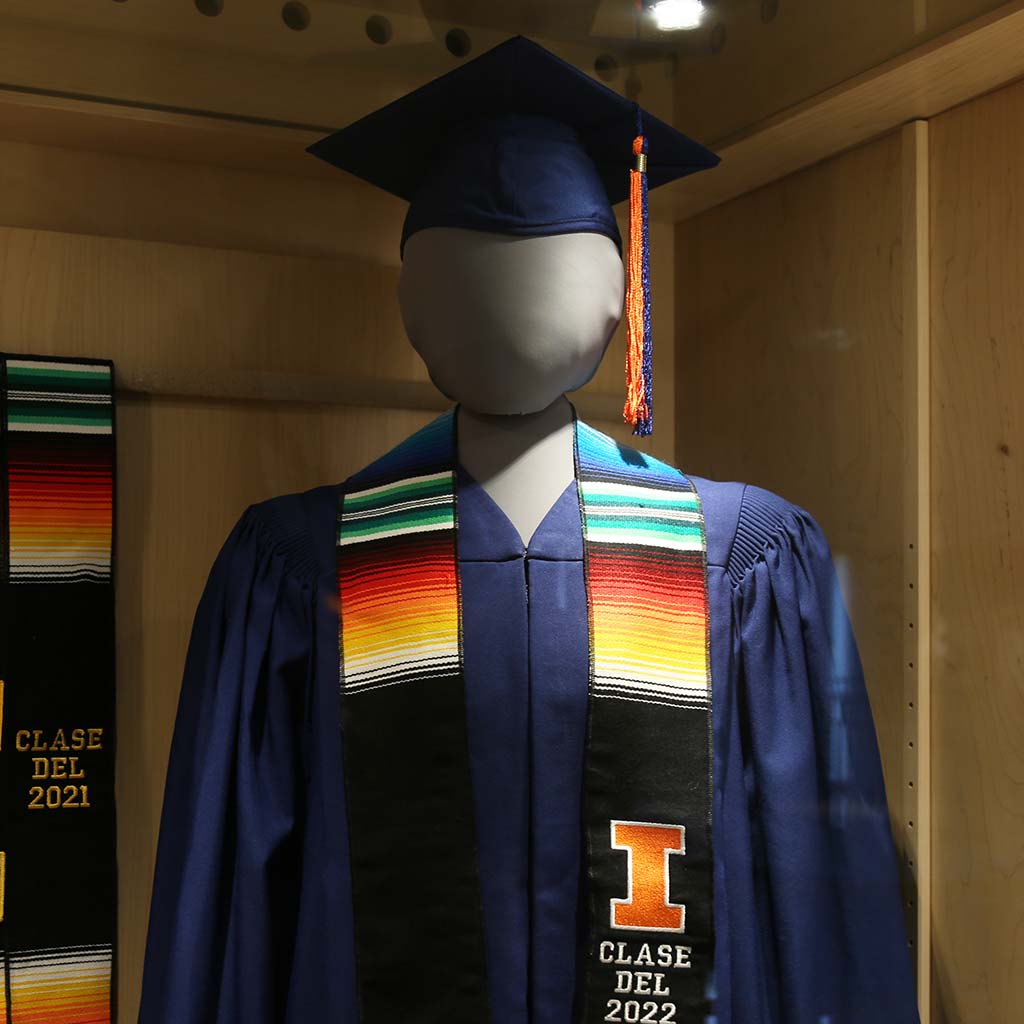 A mannequin demonstrating graduation regalia and a Latinx stole