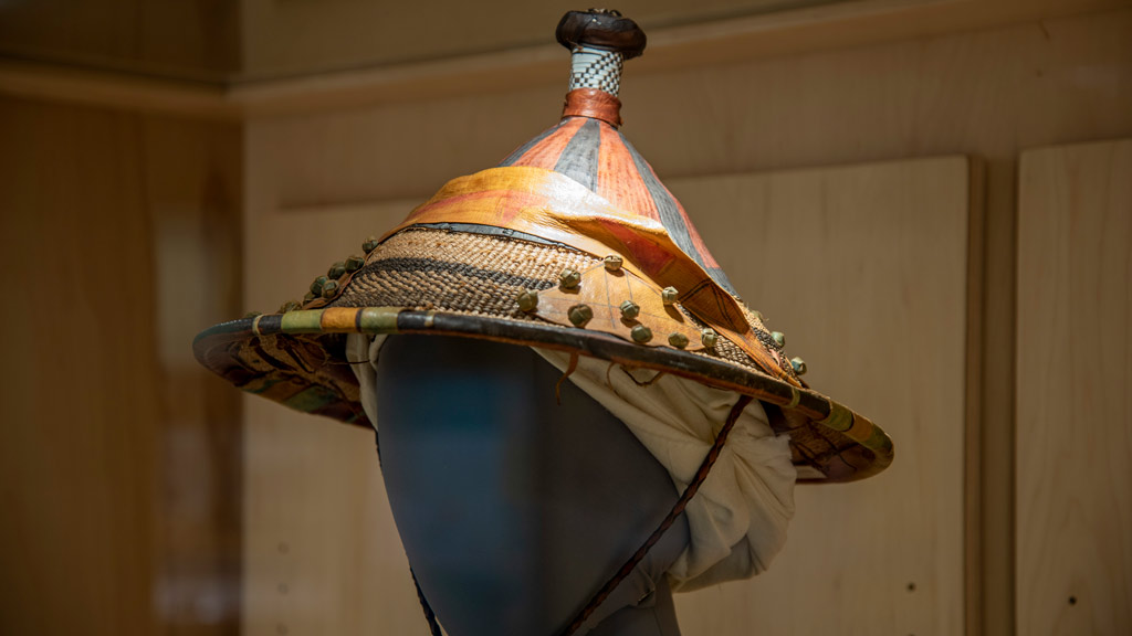 A close-up of the head of the mannequin, wearing a woven reed hat