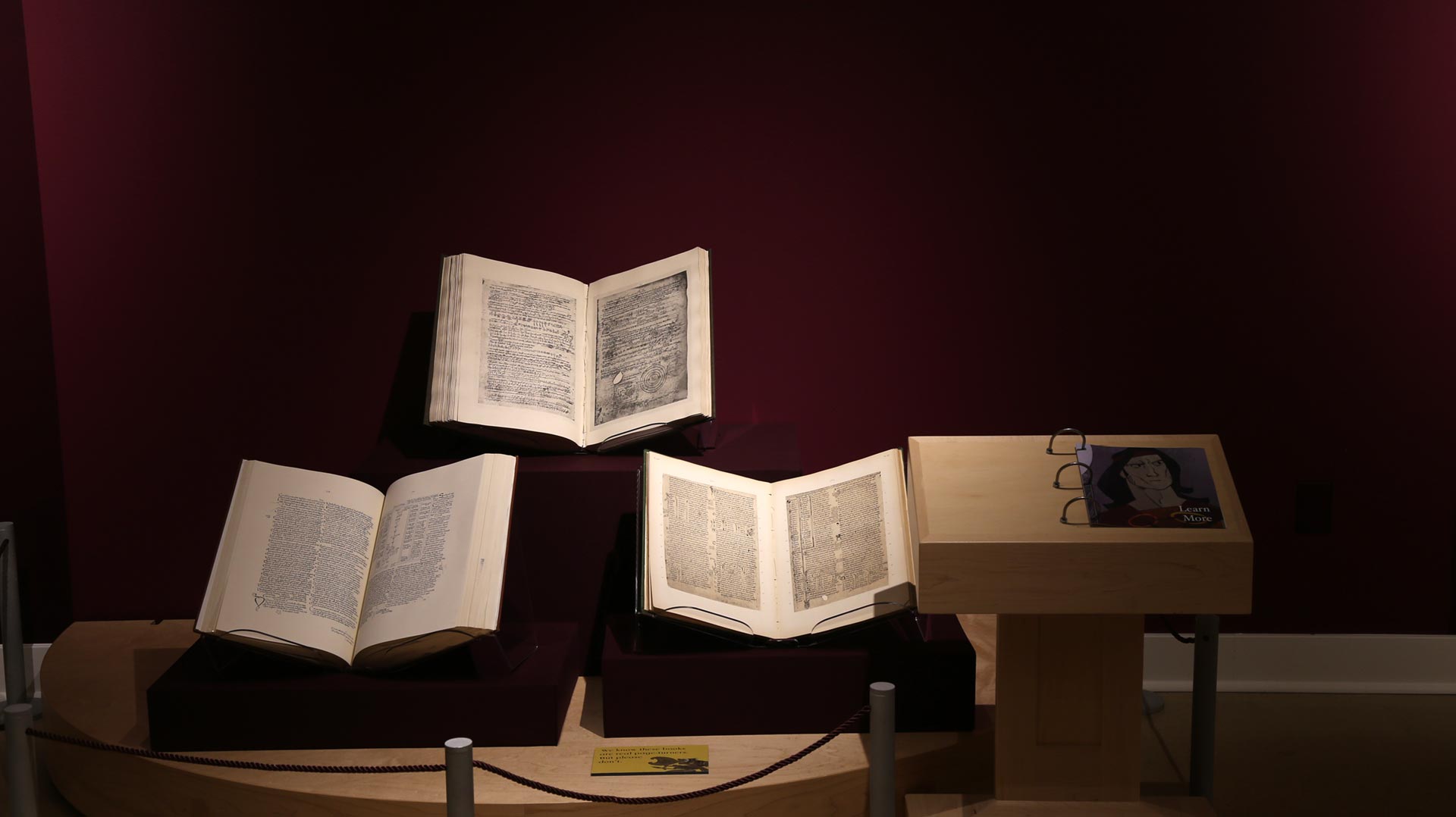 three opened books and a text description on the side