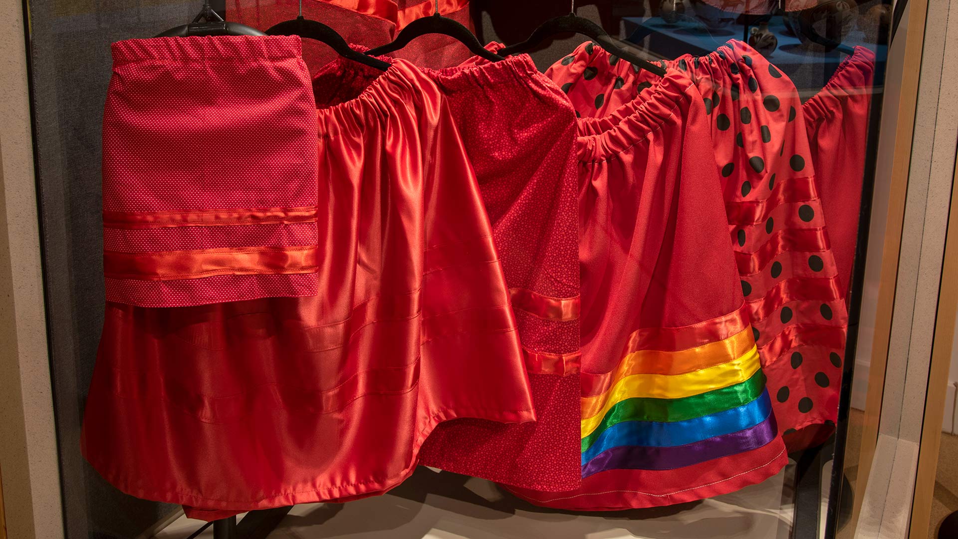 Red skirts of different lengths and designs on display with hangers