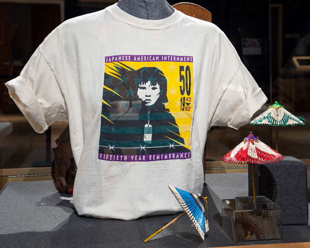three small umbrellas and a white t-shirt with a graphic representing the remembrance of japense internment