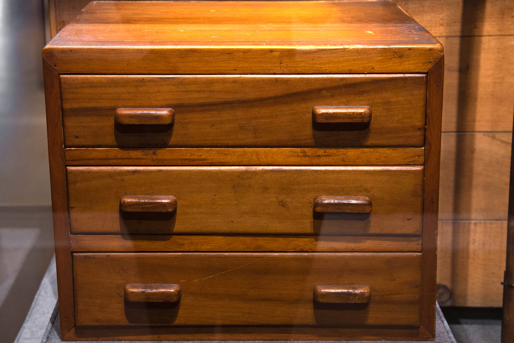 short wooden chest of drawers with two handles on each drawer