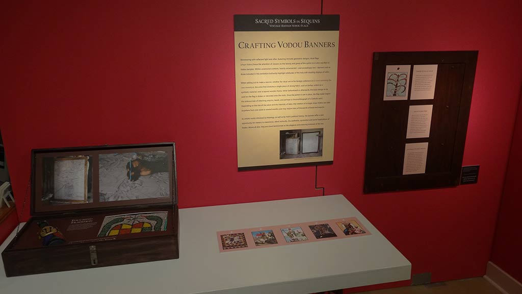 text description on the wall titled 'crafting vodou banners' and wooden case on the table