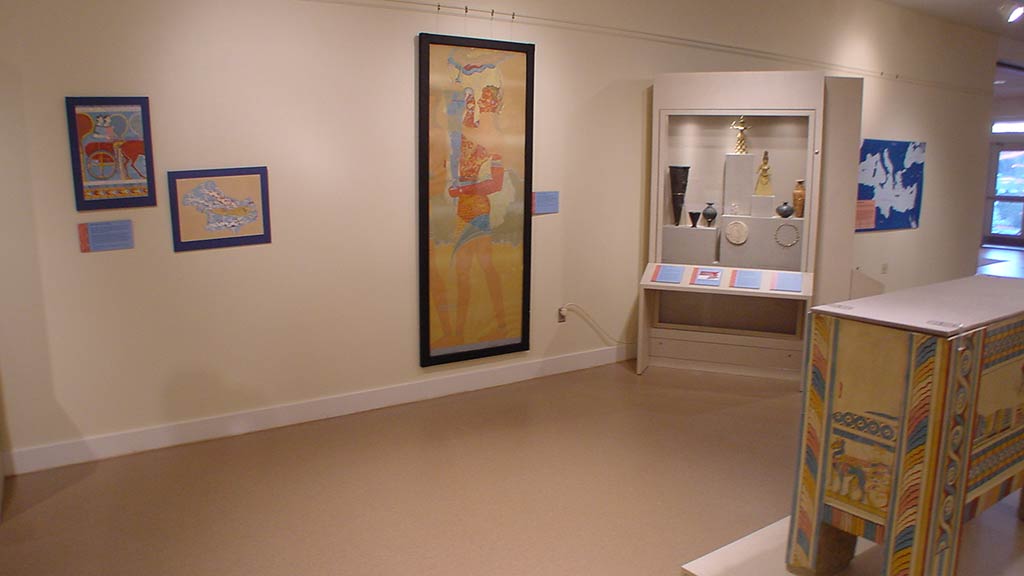 illustration hung on the wall of a man holding objects, next to a display case with artifacts
