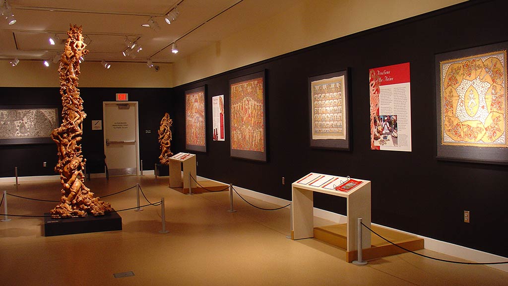 twisted wooden figures that forms a elongated sculpture, and more of the gallery can be seen