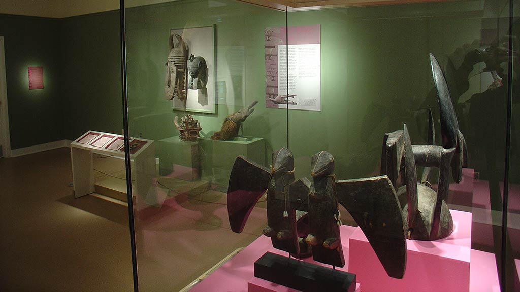 gallery view of sculptures in a case and other artifacts on display